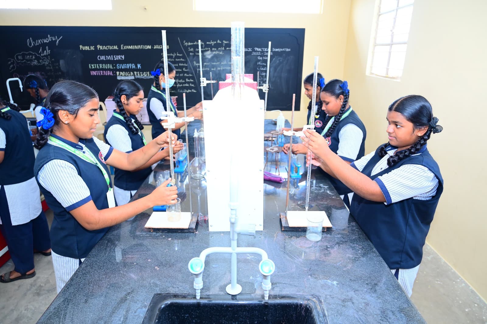 Students conducting an experiment with tall laboratory apparatus